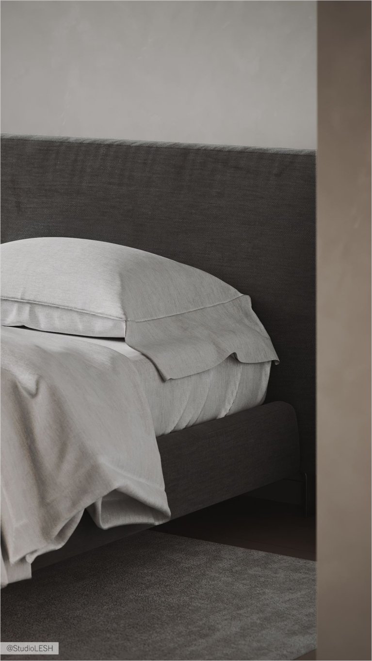 Интерьер современной спальни: кровать с мягким изголовьем из ткани серого цвета, две прикроватные тумбочки с выдвижными ящиками, серый ковер на полу, светлые стены.