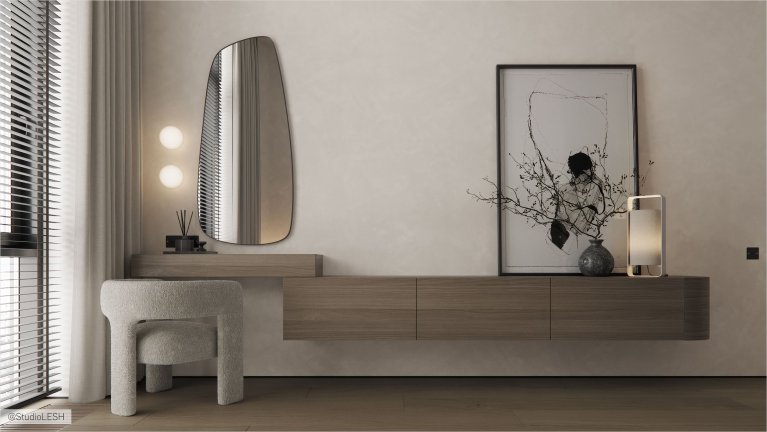 Интерьер современной комнаты с деревянным туалетным столиком, зеркалом необычной формы, мягким пуфом и картиной на стене.