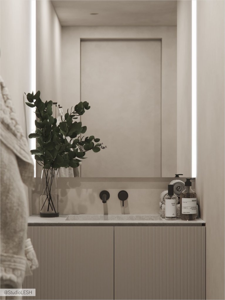 Интерьер современной ванной комнаты с большим зеркалом, подвесной тумбой с раковиной, комнатным растением и различными аксессуарами.