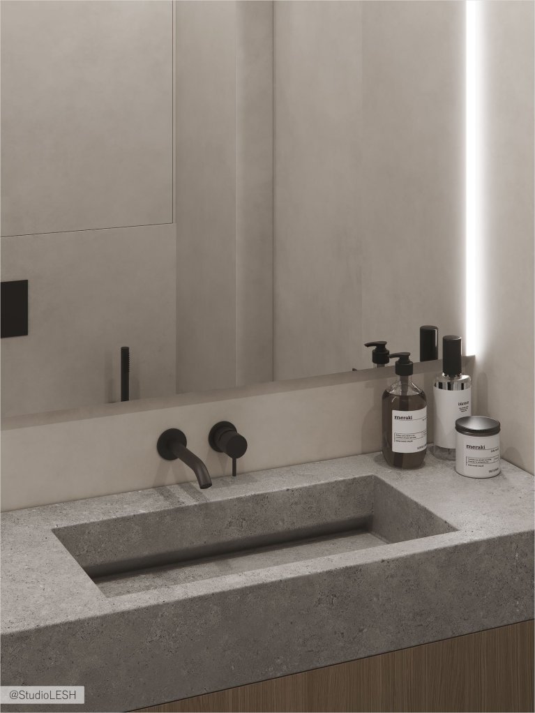 Интерьер современной ванной комнаты с минималистичным дизайном, где серый бетонный умывальник контрастирует с черным смесителем и другими темными элементами.
