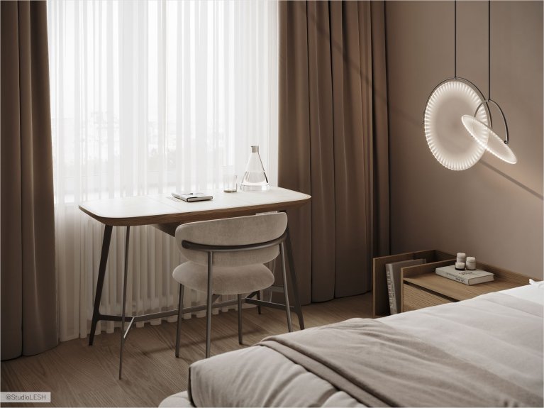 Фотография интерьера современной спальни с рабочим местом, расположенным у окна. На столе стоит ноутбук, лампа и различные предметы. В комнате белые стены, светлый паркетный пол и много естественного света, поступающего через большое окно, зашторенное полупрозрачной шторой. Рядом с рабочим местом находится кровать с серым постельным бельем