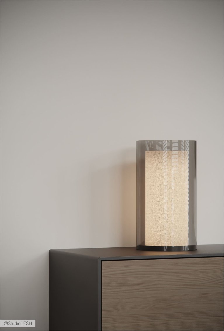 Крупный план настольной лампы с цилиндрическим абажуром из ткани, стоящей на деревянном комоде с выдвижными ящиками. Стена за лампой однотонная, светлая