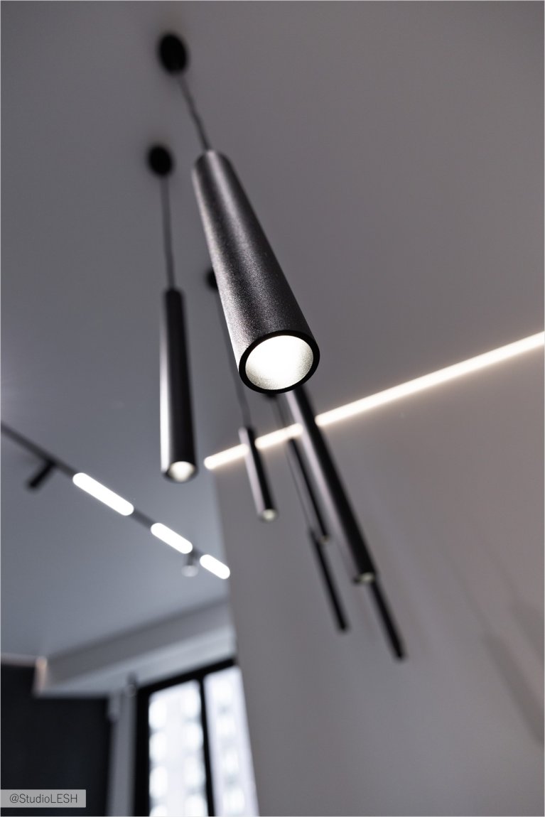 Стильные черные светильники с лаконичным дизайном, идеально подходящие для современного интерьера. Светильники подвешены на разной высоте, создавая динамичную композицию. Яркий свет, исходящий от светильников, подчеркивает их форму и текстуру