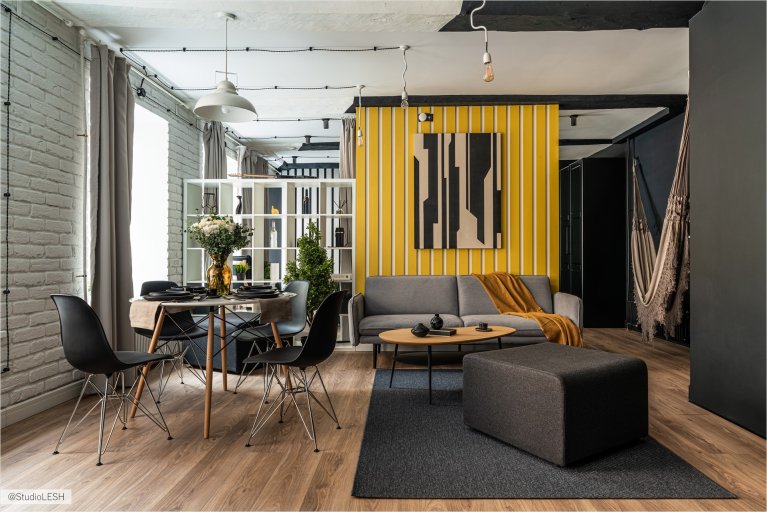 Интерьер гостиной с элементами лофт-стиля и акцентными деталями, такими как картина и декоративные элементы