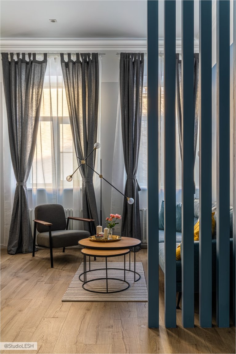 Серый диван с подушками и пледом в гостиной, создающий уютную атмосферу