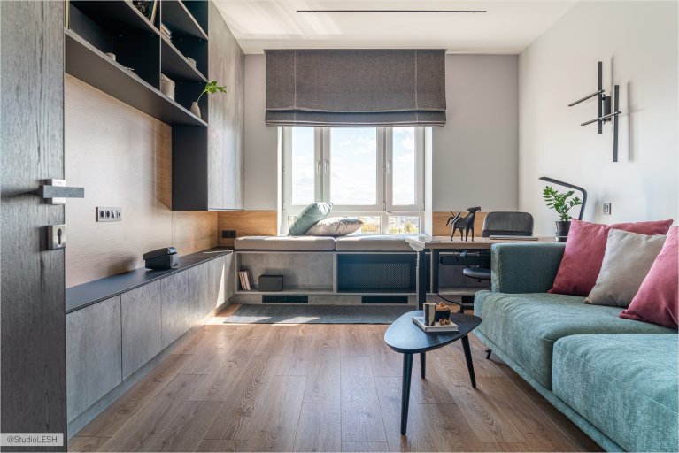 Современная гостиная с диваном, рабочим местом у окна и стильными элементами декора